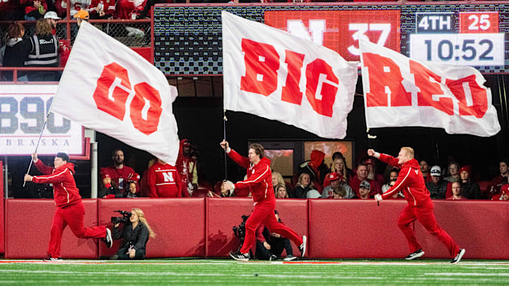 Nov 23, 2024; Lincoln, Nebraska, USA; Nebraska Cornhuskers cheerleaders carry flags across the field after a score against the Wisconsin Badgers during the fourth quarter at Memorial Stadium. Nov 23, 2024; Lincoln, Nebraska, USA; Nebraska Cornhuskers cheerleaders carry flags across the field after a score against the Wisconsin Badgers during the fourth quarter at Memorial Stadium.