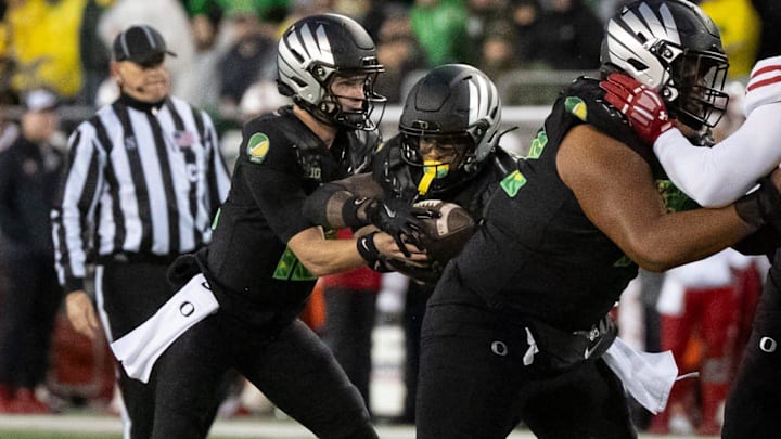 Oregon quarterback Brock Thomas, left, hands off the ball to running back Jordon Davison as the Oregon Ducks host the Wisconsin Badgers on Oct. 25, 2025, at Autzen Stadium in Eugene, Oregon.