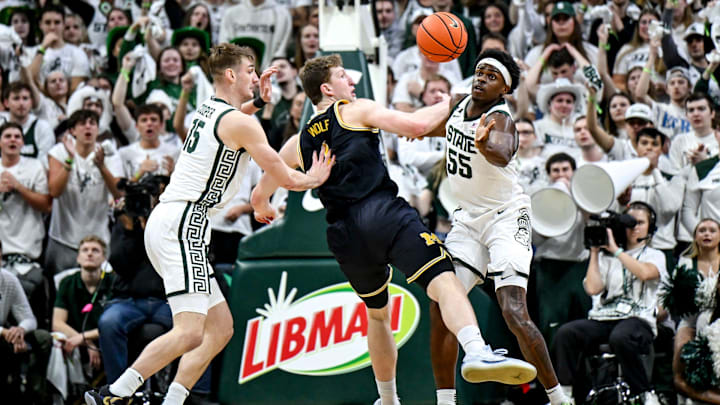 Michigan State's Coen Carr, right, knocks the ball from Michigan's Danny Wolf's hands as Carson Cooper, left, defends during the first half on Sunday, March 9, 2025, at the Breslin Center in East Lansing.