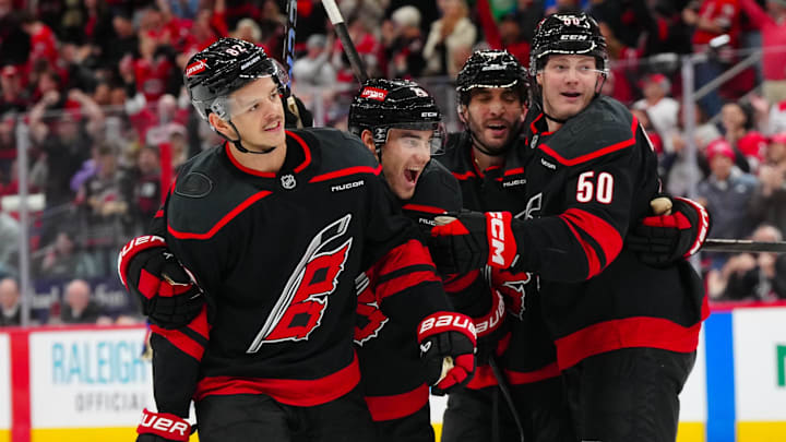 Nov 27, 2024; Raleigh, North Carolina, USA;  Carolina Hurricanes center Jesperi Kotkaniemi (82) is congratulated by defenseman Sean Walker (26) defenseman Shayne Gostisbehere (4) and left wing Eric Robinson (50) after his goal against the New York Rangers during the third period at Lenovo Center. Mandatory Credit: James Guillory-Imagn Images