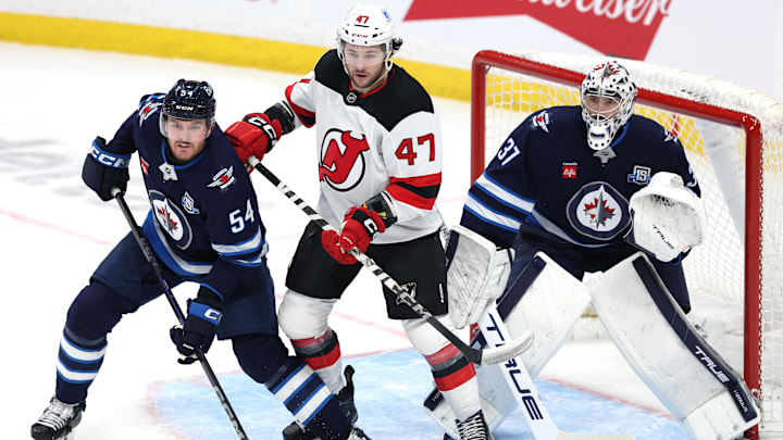 New Jersey Devils left wing Paul Cotter and Winnipeg Jets goaltender Connor Hellebuyck: James Carey Lauder-Imagn Images