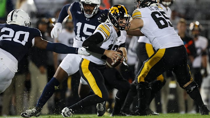 Sep 23, 2023; University Park, Pennsylvania, USA; Iowa Hawkeyes quarterback Cade McNamara (12) scrambles with the ball while avoiding a tackle during the first quarter against the Penn State Nittany Lions at Beaver Stadium. Penn State defeated Iowa 31-0. Mandatory Credit: Matthew O'Haren-USA TODAY Sports