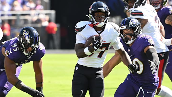 Houston Texans running back Woody Marks (27) runs for a gain past Baltimore Ravens linebacker Tavius Robinson (95) and linebacker Teddye Buchanan (40) during the first quarter at M&T Bank Stadium.
