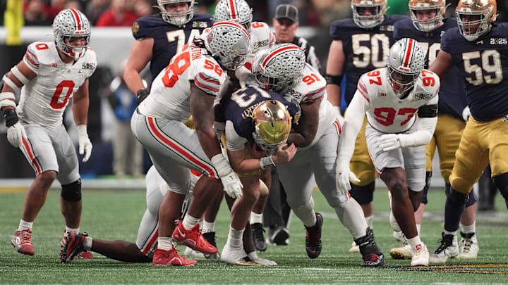 Jan 20, 2025; Atlanta, GA, USA; Notre Dame Fighting Irish quarterback Riley Leonard (13) is tackled by Ohio State Buckeyes defensive tackle Ty Hamilton (58) and Ohio State Buckeyes defensive tackle Tyleik Williams (91) in the CFP National Championship college football game at Mercedes-Benz Stadium.