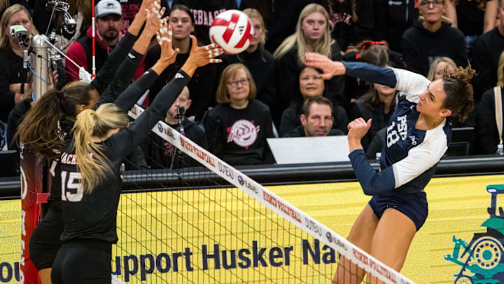 Penn State Nittany Lions right side hitter Kennedy Martin (18) attacks Nebraska Cornhuskers middle blocker Andi Jackson (15) and outside hitter Harper Murray (27)