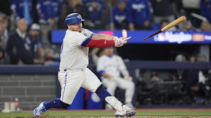 Kirk breaking his bat on a double play in a white unifor