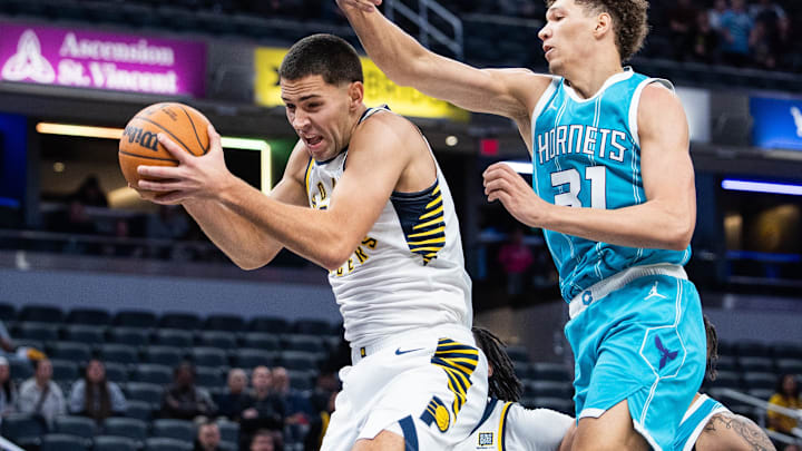 Oct 17, 2024; Indianapolis, Indiana, USA; Indiana Pacers forward Cole Swider (21) rebounds the ball while Charlotte Hornets forward Tidjane Salaun (31)  defends in OT at Gainbridge Fieldhouse. Mandatory Credit: Trevor Ruszkowski-Imagn Images