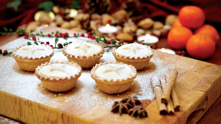 Festive scene with mince pies alongside tangerines, nuts and cinnamon sticks