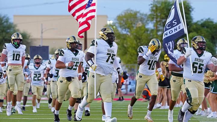 Basha tackle Dajohn Yarborough (75) carries out the American flag before a 2025 games against Brophy Prep.