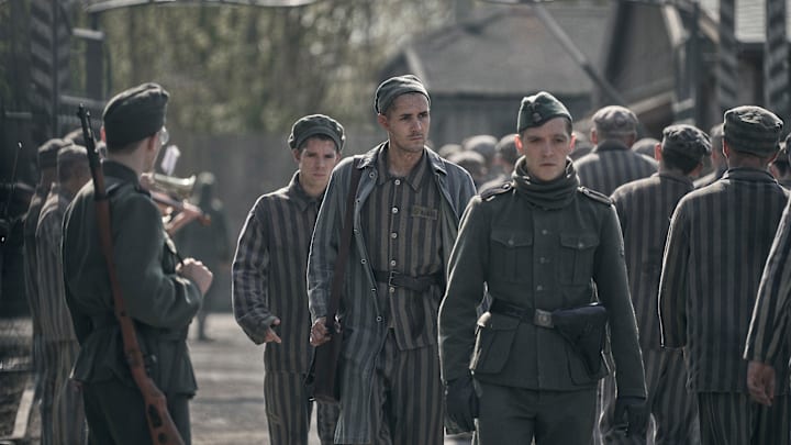 Jonah Hauer-King as Lali Sokolov seen here walking through Auschwitz with German-born actor Jonas Nay as Nazi officer Stefan Baretzki, front right