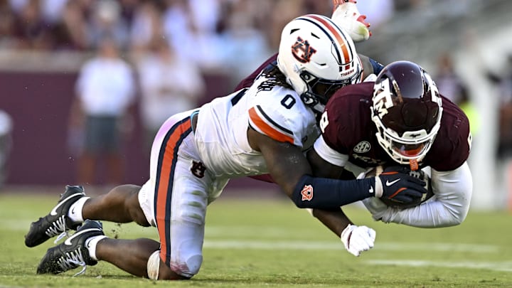 Sep 27, 2025; College Station, Texas, USA; Auburn Tigers linebacker Robert Woodyard Jr. (0) wraps up Texas A&M Aggies running back Le'Veon Moss (8) during the third quarter at Kyle Field. Mandatory Credit: Maria Lysaker-Imagn Images 