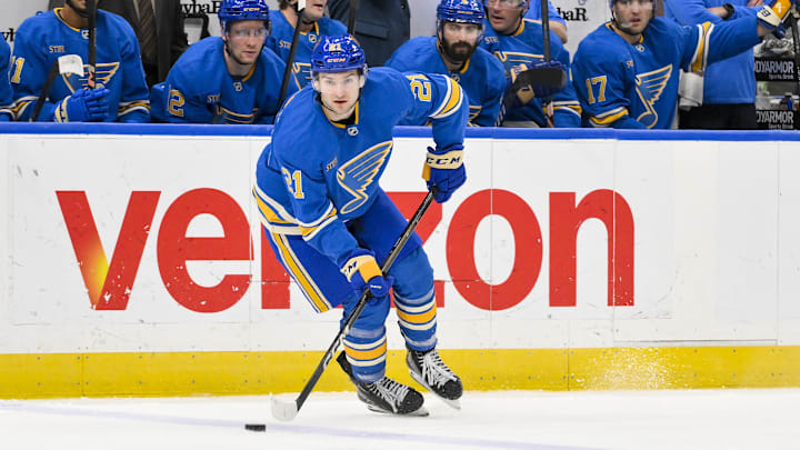 Apr 5, 2025; St. Louis, Missouri, USA;  St. Louis Blues right wing Jimmy Snuggerud (21) controls the puck against the Colorado Avalanche during the second period at Enterprise Center. Mandatory Credit: Jeff Curry-Imagn Images