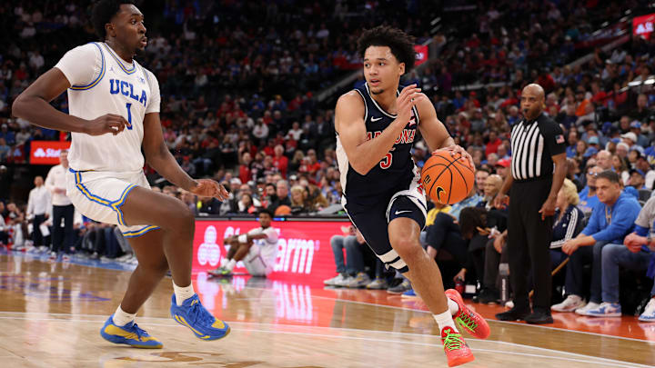 Nov 14, 2025; Inglewood, California, USA;  Arizona Wildcats guard Brayden Burries (5) drives to the basket against UCLA Bruins center Xavier Booker (1) during the first half of the Hall of Fame Series game at Intuit Dome. Mandatory Credit: Kiyoshi Mio-Imagn Images