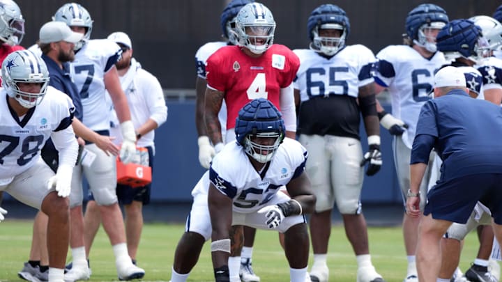 Dallas Cowboys quarterback Dak Prescott prepares to take the snap as guard Tyler Booker reacts at training camp.