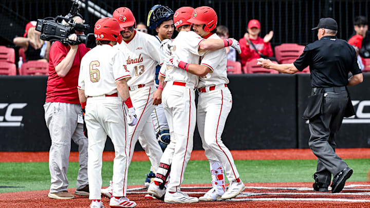 Louisville baseball players celebrate at home plate after a home run.