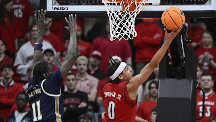 Feb 21, 2026; Louisville, Kentucky, USA;  Louisville Cardinals guard Mikel Brown Jr. (0) shoots against Georgia Tech Yellow Jackets forward Baye Ndongo (11) during the first half at KFC Yum! Center. Mandatory Credit: Jamie Rhodes-Imagn Images