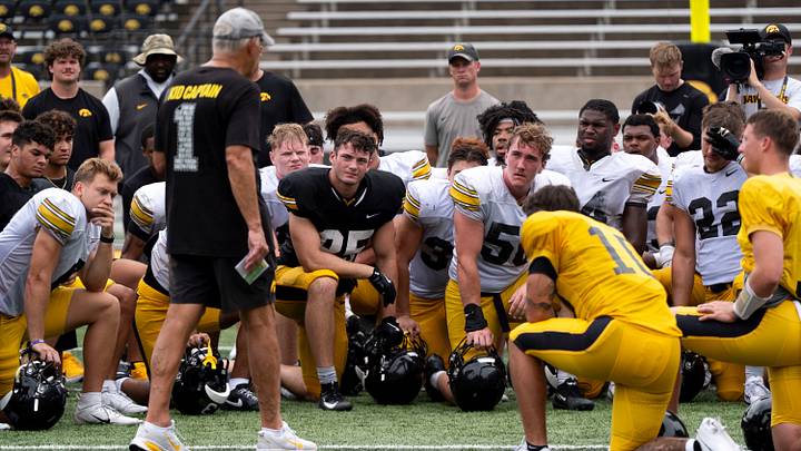 Players take a knee as Iowa head coach Kirk Ferentz talks to the team Aug. 15, 2026 during the Kids Day at Kinnick open practice at Kinnick Stadium in Iowa City, Iowa.