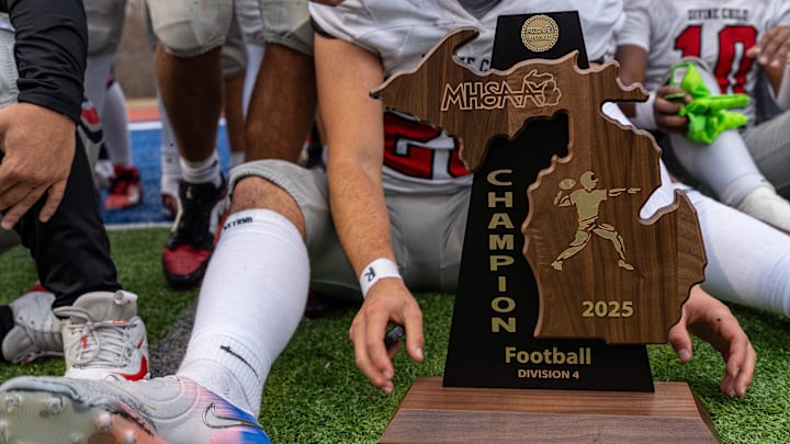 A Divine Child player holds a MHSAA Division 4 regional championship trophy after defeating Harper Woods 10-6 at John Glenn High School in Westland on Saturday, Nov. 15, 2025.
