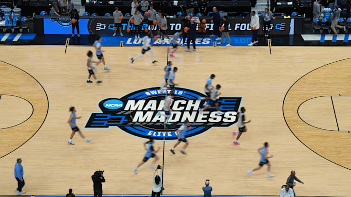 North Carolina Tar Heels players run over the March Madness logo 