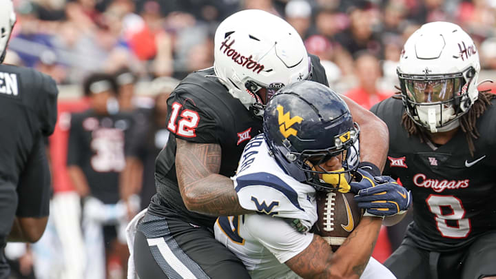 Nov 1, 2025; Houston, Texas, USA; West Virginia Mountaineers running back Diore Hubbard (20) is tackled by Houston Cougars linebacker Sione Fotu (12) in the first half at TDECU Stadium. Mandatory Credit: Thomas Shea-Imagn Images