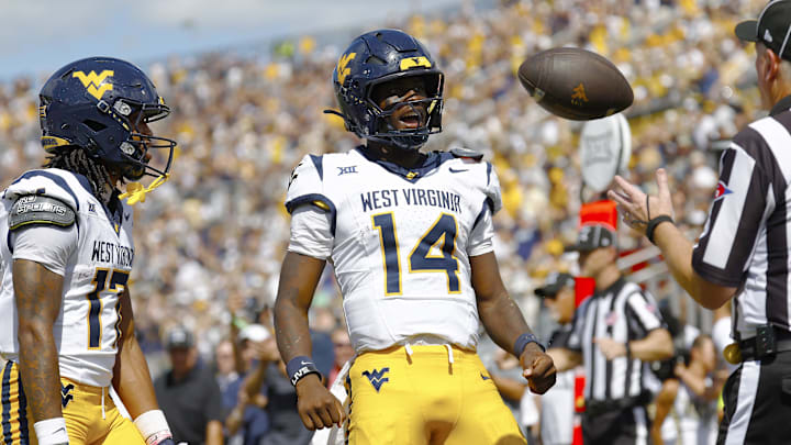 Oct 18, 2025; Orlando, Florida, USA; West Virginia Mountaineers quarterback Khalil Wilkins (14) flexes after scoring a touchdown in the first half against the Central Florida Knights at Acrisure Bounce House. Mandatory Credit: Russell Lansford-Imagn Images Oct 18, 2025; Orlando, Florida, USA; West Virginia Mountaineers quarterback Khalil Wilkins (14) flexes after scoring a touchdown in the first half against the Central Florida Knights at Acrisure Bounce House. Mandatory Credit: Russell Lansford-Imagn Images