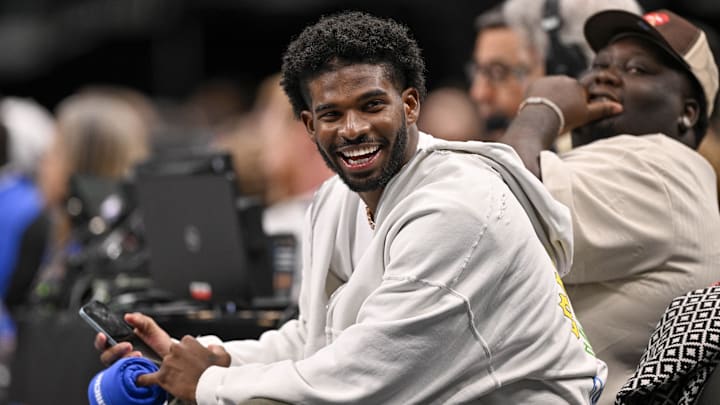 Jan 14, 2025; Dallas, Texas, USA; Colorado Buffaloes quarterback Shedeur Sanders laughs as he watches the game between the Dallas Mavericks and the Denver Nuggets during the second half at the American Airlines Center.  