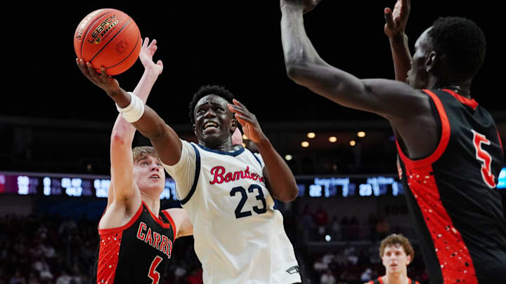 Ballard Jude Gibson (23) goes for a layup between Carroll forward Jared Mohr (4) and Carroll forward Lual Tharjiath (5) during the third quarter in the 3A IIHSAA boys basketball semifinal. on March 11, 2026, at Casey’s Center in Des Moines, Iowa.