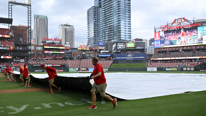 Jul 13, 2025; St. Louis, Missouri, USA;  St. Louis Cardinals grounds crew pulls the tarp on the field during a rain delay in the third inning of a game between the St. Louis Cardinals and the Atlanta Braves at Busch Stadium. Mandatory Credit: Jeff Curry-Imagn Images