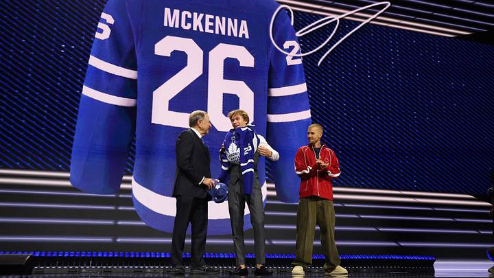 Jun 26, 2026; Buffalo, New York, USA; Gavin McKenna puts on a sweater beside NHL commissioner Gary Bettman and singer Justin Bieber after being selected with the first pick in the first round of the 2026 NHL Draft by the Toronto Maple Leafs at KeyBank Center. Mandatory Credit: Timothy T. Ludwig-Imagn Images