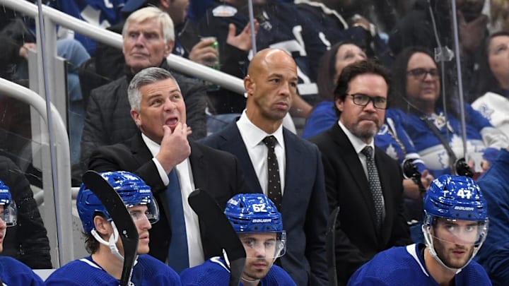 Oct 8, 2022; Toronto, Ontario, CAN;  Toronto Maple Leafs head coach Sheldon Keefe (left) looks up at the scoreboard as assistant coaches Manny Malhotra (center) and Dean Chynoweth look on during a break in play against the Detroit Red Wings at Scotiabank Arena. Mandatory Credit: Dan Hamilton-Imagn Images