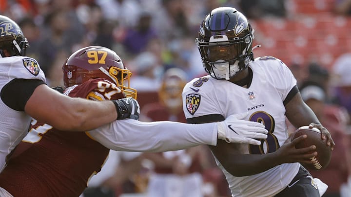 Aug 28, 2021; Landover, Maryland, USA; Baltimore Ravens quarterback Lamar Jackson (8) scrambles from Washington Football Team defensive tackle Tim Settle (97) at FedExField. Mandatory Credit: Geoff Burke-Imagn Images