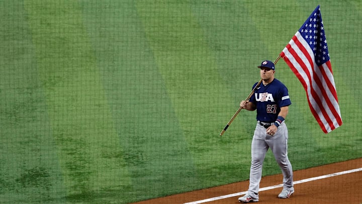 Mar 21, 2023; Miami, Florida, USA; USA center fielder Mike Trout (27) carries the American flag as he enters the ballpark for team introductions against Japan at LoanDepot Park. Mandatory Credit: Rhona Wise-Imagn Images