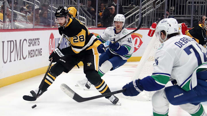 Nov 27, 2024; Pittsburgh, Pennsylvania, USA;  Pittsburgh Penguins defenseman Marcus Pettersson (28) moves the puck against Vancouver Canucks center Elias Pettersson (40) and Vancouver Canucks left wing Jake DeBrusk (74) during the second period at PPG Paints Arena. Mandatory Credit: Charles LeClaire-Imagn Images