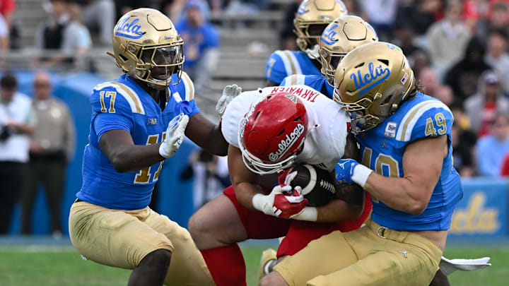 Nov 30, 2024; Pasadena, California, USA; UCLA Bruins linebacker Jalen Woods (17), defensive back Jaylin Davies (6), and linebacker Carson Schwesinger (49) tackle Fresno State Bulldogs tight end Jake Tarwater (87) during the third quarter at Rose Bowl. Mandatory Credit: Robert Hanashiro-Imagn Images