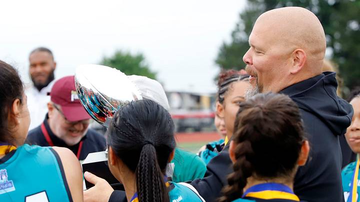 Eagles coach Tim Quinn holds the Big 33 flag football championship trophy Sunday at Chapman Field. Philadelphia beat the Commanders 21-13 to claim their third straight title.
