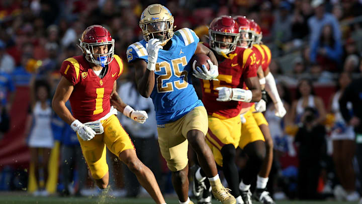 Nov 18, 2023; Los Angeles, California, USA; UCLA Bruins running back TJ Harden (25) runs against USC Trojans cornerback Domani Jackson (1) and safety Anthony Beavers Jr. (15) during the third quarter at United Airlines Field at Los Angeles Memorial Coliseum. Mandatory Credit: Jason Parkhurst-Imagn Images Nov 18, 2023; Los Angeles, California, USA; UCLA Bruins running back TJ Harden (25) runs against USC Trojans cornerback Domani Jackson (1) and safety Anthony Beavers Jr. (15) during the third quarter at United Airlines Field at Los Angeles Memorial Coliseum. Mandatory Credit: Jason Parkhurst-Imagn Images