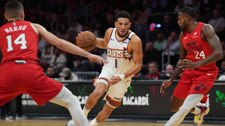 Dec 7, 2024; Miami, Florida, USA;  Phoenix Suns guard Devin Booker (1) brings the ball up the court against Miami Heat guard Tyler Herro (14) and forward Haywood Highsmith (24) during the first half at Kaseya Center. Mandatory Credit: Jim Rassol-Imagn Images