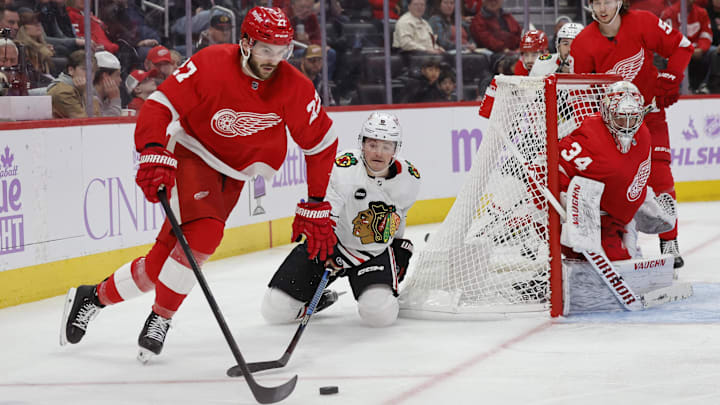 Nov 30, 2023; Detroit, Michigan, USA; Detroit Red Wings center Michael Rasmussen (27) skates with the puck chased by Chicago Blackhawks center Ryan Donato (8) in the third period at Little Caesars Arena. Mandatory Credit: Rick Osentoski-Imagn Images