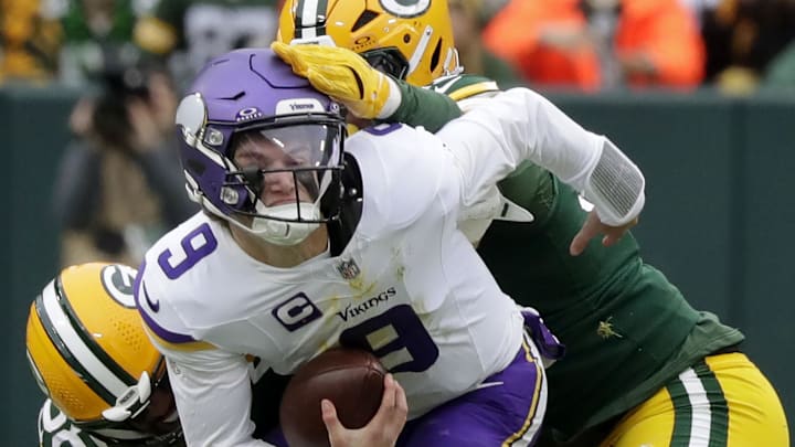 Green Bay Packers defenders Isaiah McDuffie and Warren Brinson (91) sack Minnesota Vikings quarterback J.J. McCarthy.