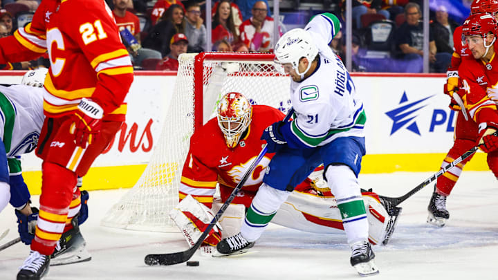 Sep 28, 2024; Calgary, Alberta, CAN; Calgary Flames goaltender Devin Cooley (1) guards his net against Vancouver Canucks left wing Nils Hoglander (21) during the third period at Scotiabank Saddledome. Mandatory Credit: Sergei Belski-Imagn Images
