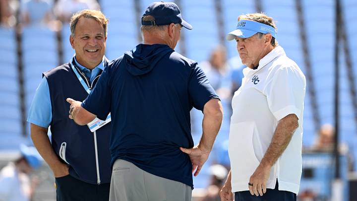 Sep 13, 2025; Chapel Hill, North Carolina, USA; Richmond Spiders head coach Russ Huesman talks to North Carolina Tar Heels general manger Michael Lombardi and head coach Bill Belichick before the game at Kenan Stadium. Mandatory Credit: Bob Donnan-Imagn Images