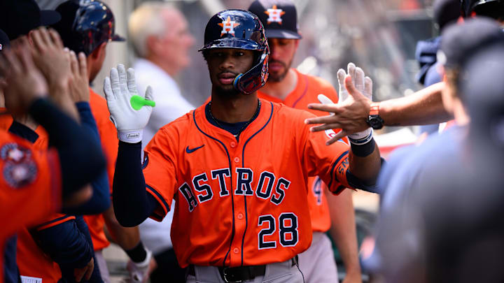 Houston Astros infielder Brice Matthews celebrates with teammates in the dugout after a home run, wearing an orange jersey. 