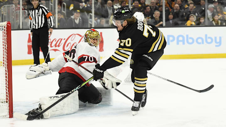 Mar 19, 2024; Boston, Massachusetts, USA;  Boston Bruins center Jesper Boqvist (70) tucks the puck past Ottawa Senators goaltender Joonas Korpisalo (70) during the third period at TD Garden. Mandatory Credit: Bob DeChiara-Imagn Images