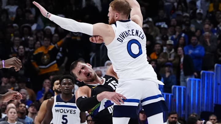 Dec 25, 2025; Denver, Colorado, USA; Minnesota Timberwolves guard Donte Divincenzo (0) fouls Denver Nuggets center Nikola Jokic (15) in overtime at Ball Arena. Mandatory Credit: Ron Chenoy-Imagn Images