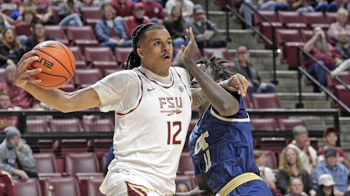 Jan 18, 2025; Tallahassee, Florida, USA;  Florida State Seminoles forward Malique Ewin (12) drives the ball past Georgia Tech Yellowjackets forward Baye Ndongo (11) during the first half at Donald L. Tucker Center. Mandatory Credit: Robert Myers-Imagn Images