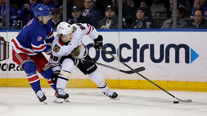 Dec 9, 2024; New York, New York, USA; New York Rangers defenseman Zac Jones (6) and Chicago Blackhawks center Connor Bedard (98) fight for the puck during the second period at Madison Square Garden. Mandatory Credit: Brad Penner-Imagn Images