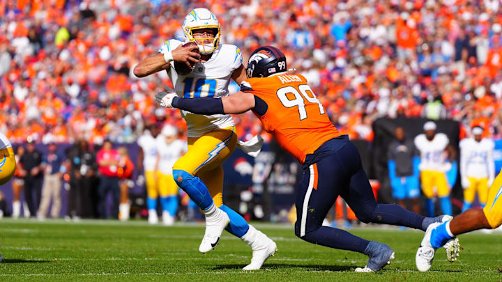 Oct 13, 2024; Denver, Colorado, USA; Denver Broncos defensive end Zach Allen (99) reaches for Los Angeles Chargers quarterback Justin Herbert (10) in the second quarter at Empower Field at Mile High.