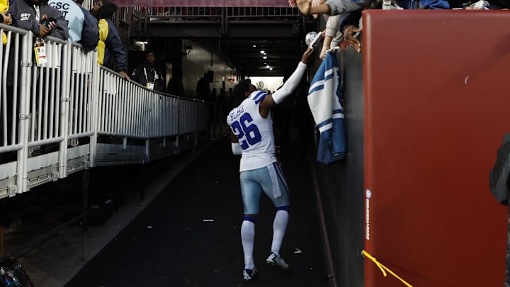 Dallas Cowboys cornerback DaRon Bland hands a piece of his equipment to a fan while leaving the field.