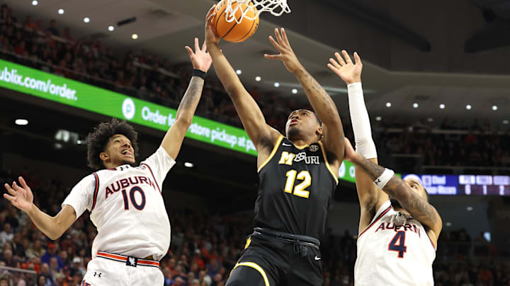Jan 4, 2025; Auburn, Alabama, USA;  Missouri Tigers guard Tony Perkins (12) takes a shot between Auburn Tigers guard Chad Baker-Mazara (10) and forward Johni Broome (4) during the first half at Auburn Arena. Mandatory Credit: John Reed-Imagn Images