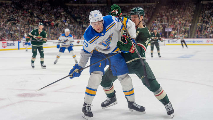 Mar 1, 2026; Saint Paul, Minnesota, USA; St. Louis Blues defenseman Logan Mailloux (23) is checked by Minnesota Wild center Joel Eriksson Ek (14) in the second period at Grand Casino Arena. Mandatory Credit: Matt Blewett-Imagn Images